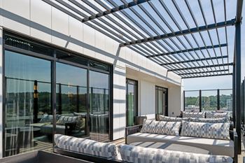 A modern patio with a glass wall and a metal pergola