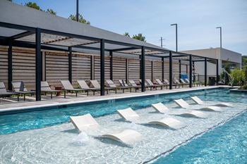 A pool with white loungers and a blue sky in the background
