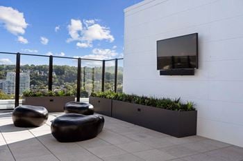 A balcony with a black railing, a white wall, and a flat screen tv mounted on it