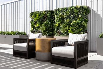 A set of three outdoor chairs with cushions and a small table with a gold-colored top