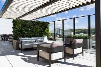 A patio with a couch, chairs and a table with a view of the city