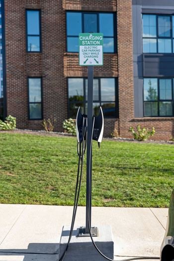 A charging station sign is on a pole in front of a building