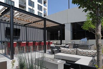 A modern outdoor seating area with red chairs and a glass table