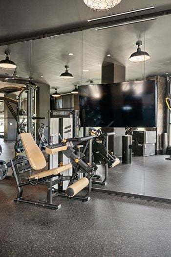 A gym with a rowing machine and a television