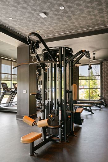 A gym with a lot of machines and chairs in it