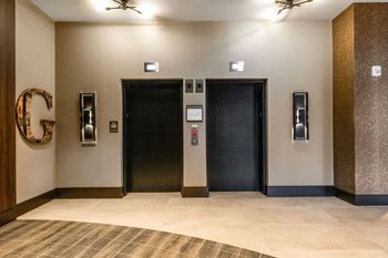A hallway with two elevators and a large letter g on the wall