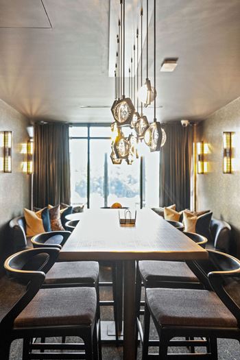 A long wooden table with chairs and a chandelier hangs from the ceiling