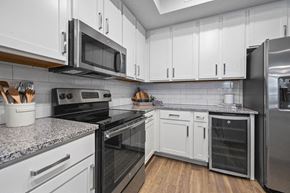 Naples apartment for rent - a kitchen with white cabinets and stainless steel appliances including a wine refrigerator at Inspira, Florida, 34113