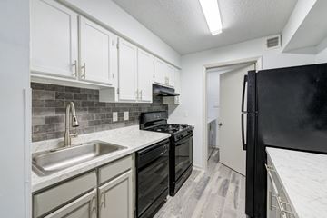 Raleigh apartment for rent - A kitchen with black appliances and white cabinets.