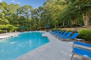 Raleigh apartment for rent - A large outdoor swimming pool surrounded by trees and lounge chairs.