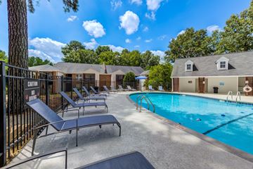 Raleigh apartment for rent - A pool area with sun loungers and a building in the background.