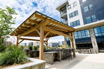 An outdoor patio with a stone wall and a wooden pergola