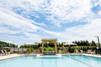 A pool with a wood pergola and lounge chairs next to it