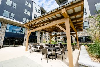 An outdoor patio with a pergola and tables and chairs