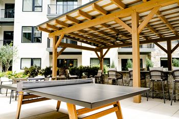 A patio with a ping pong table and a pergola