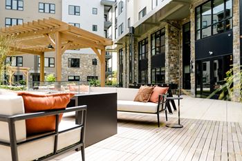 A patio with a white couch and orange pillows