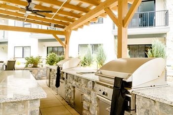 An outdoor kitchen with stone countertops and stainless steel appliances