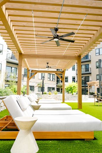 A patio with white couches and a wooden pergola