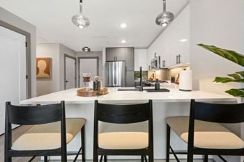 An open kitchen with an island and three chairs