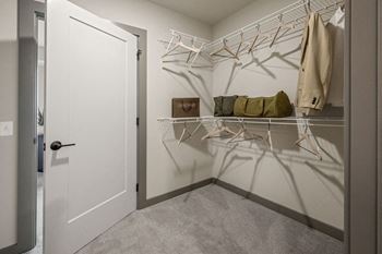 A white door is open to a hallway with a coat hanging on a rack