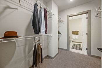 A white closet with clothes hanging on a rail