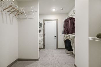 A walk in closet in a home with white walls and a white closet door