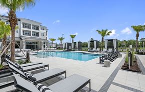Orlando apartment for rent - a swimming pool with lounge chairs and a building in the background at Madison Waterford Lakes, Orlando, 32826