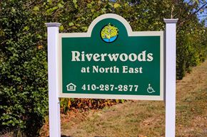North East apartment for rent - a sign for riverwoods at north east with trees in the background