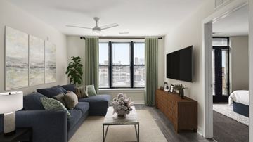 Baltimore apartment for rent - A living room with a blue couch and a flat screen TV mounted on the wall.