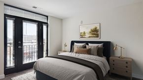 Baltimore apartment for rent - A bedroom with a large bed, a nightstand, and a painting on the wall.