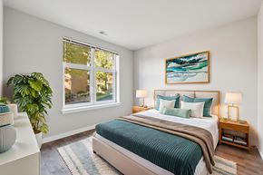 Washington apartment for rent - A bedroom with a bed, a potted plant, and a painting on the wall.