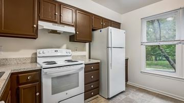 Silver Spring townhouse for rent - A white stove and refrigerator in a kitchen with brown cabinets.