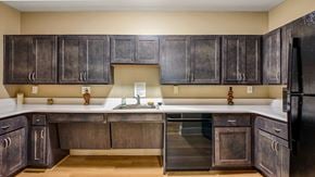 Ellicott City apartment for rent - A kitchen with dark wood cabinets and a black refrigerator.