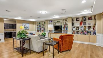 Ellicott City apartment for rent - A living room with a fireplace, a couch, a chair, and a bookshelf filled with books.