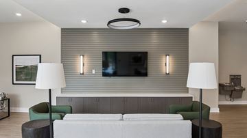 Richmond apartment for rent - A modern living room with a grey sofa, green armchair, and a television mounted on the wall.