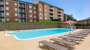 Washington apartment for rent - A swimming pool with sun loungers and a red umbrella in front of a brick building.