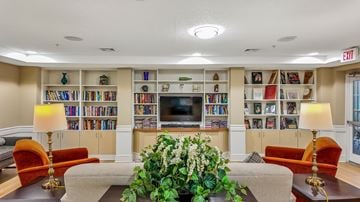 Ellicott City apartment for rent - A living room with a large bookshelf filled with books and a flat screen TV mounted on the wall.