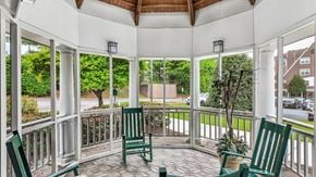 Ellicott City apartment for rent - A white gazebo with a wooden roof and a white railing with a green chair and a potted plant.