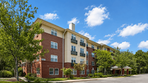 Elkridge apartment for rent - A red brick apartment building with a green tree in front.