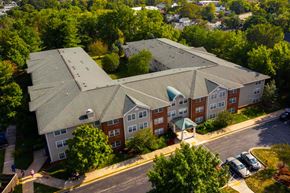 Rosedale apartment for rent - A large apartment complex with a green roof and a parking lot in front.