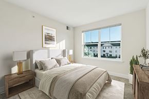 La Plata apartment for rent - A bedroom with a large bed, a nightstand with a lamp, and a window overlooking a building.