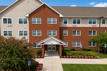 Randallstown apartment for rent - A red brick building with a covered walkway leading to the entrance.