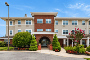 York apartment for rent - A large building with a red brick entrance and a landscaped front yard.