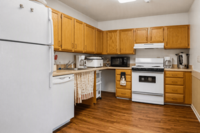 York apartment for rent - A community kitchen with wooden cabinets and white appliances.