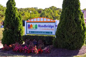Edgewood apartment for rent - the sign for woodbridge commons in front of trees and flowers