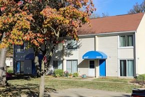 Columbia apartment for rent - A tree with orange leaves in front of a building with a blue awning.