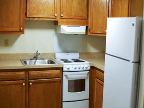 Westminster apartment for rent - a kitchen with white appliances and wooden cabinets