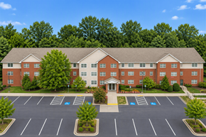 Randallstown apartment for rent - A large red brick building with a parking lot in front.