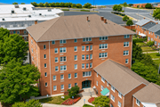 Towson apartment for rent - A large red brick building with a green roof and a courtyard in front.