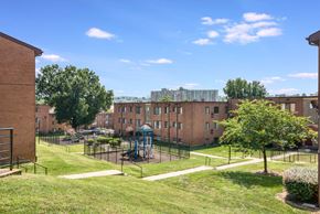 Washington apartment for rent - Exterior view of Meadowbrook Run Apartments, an Enterprise community in Congress Heights, Washington, D.C., surrounded by mature trees and green space, showcasing a peaceful park-like setting.